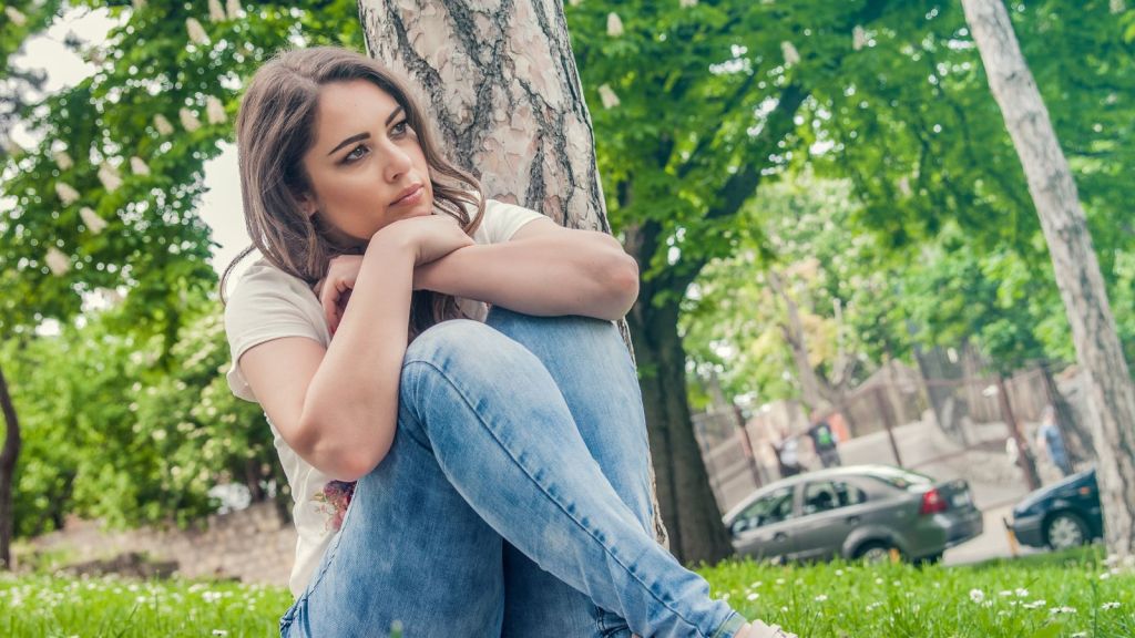 Woman sitting alone outdoors and feeling sad