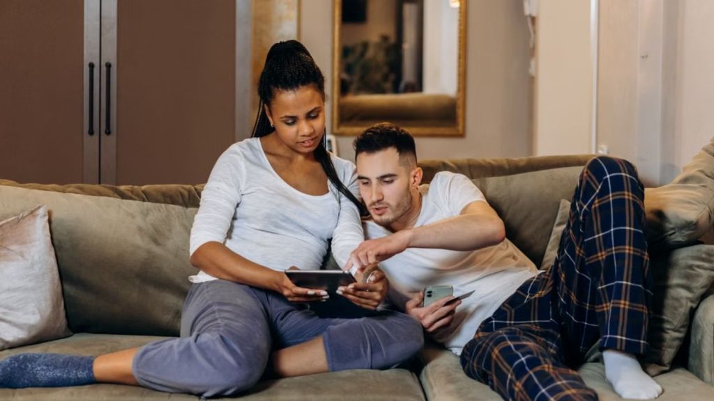 Man and woman sitting on the couch closely while looking at a tablet