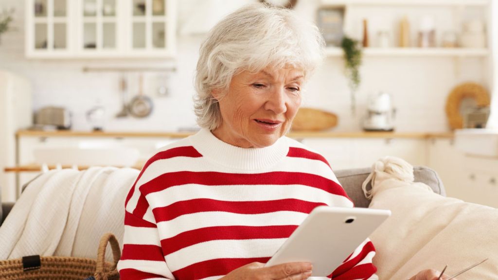 Grandmother sitting on a couch and looking at her electronic device