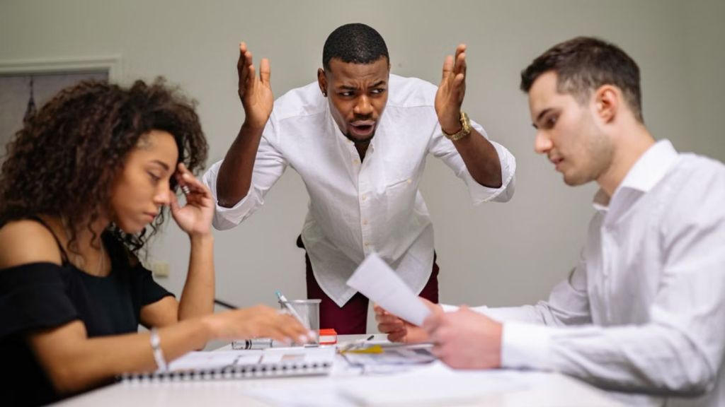 Boss feeling upset and scolding two employees in a conference room