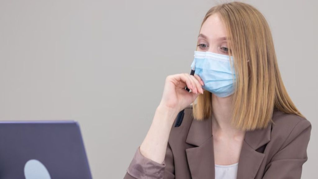 Woman wearing a face mask working in front of her laptop in the office
