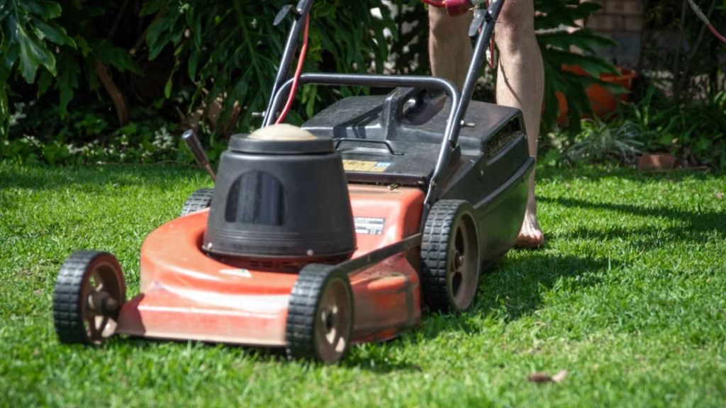 A person mowing the grass using a lawn mower