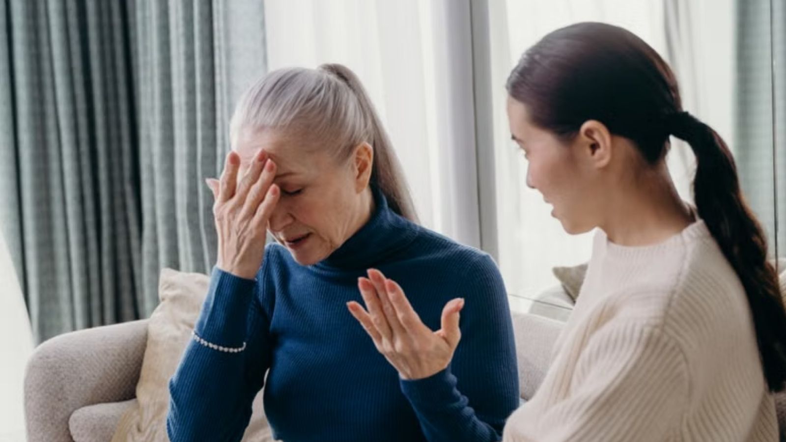 An older woman and a younger woman having an emotional conversation at home