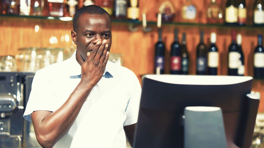 worried bartender looking at cash register