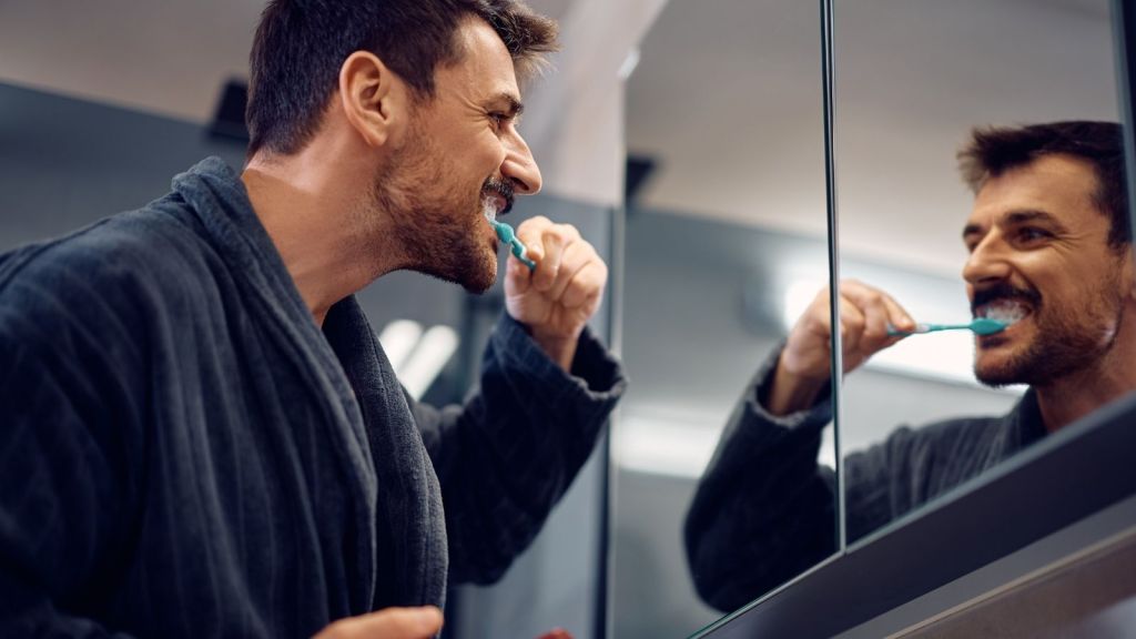 man brushing his teeth in the bathroom