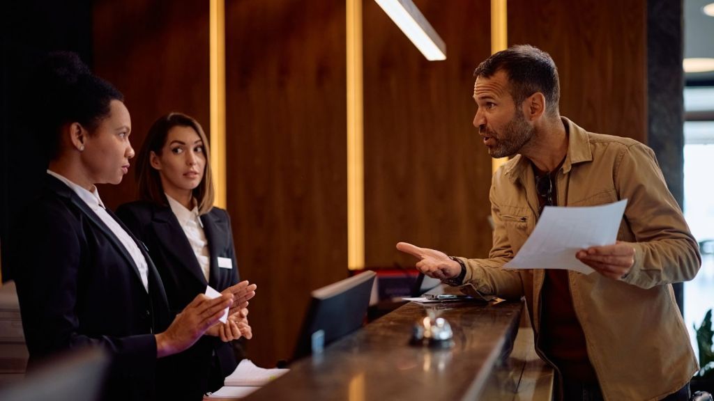 angry man yelling at hotel front desk staff