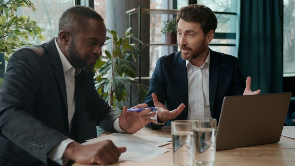 two businessmen talking and looking at a computer