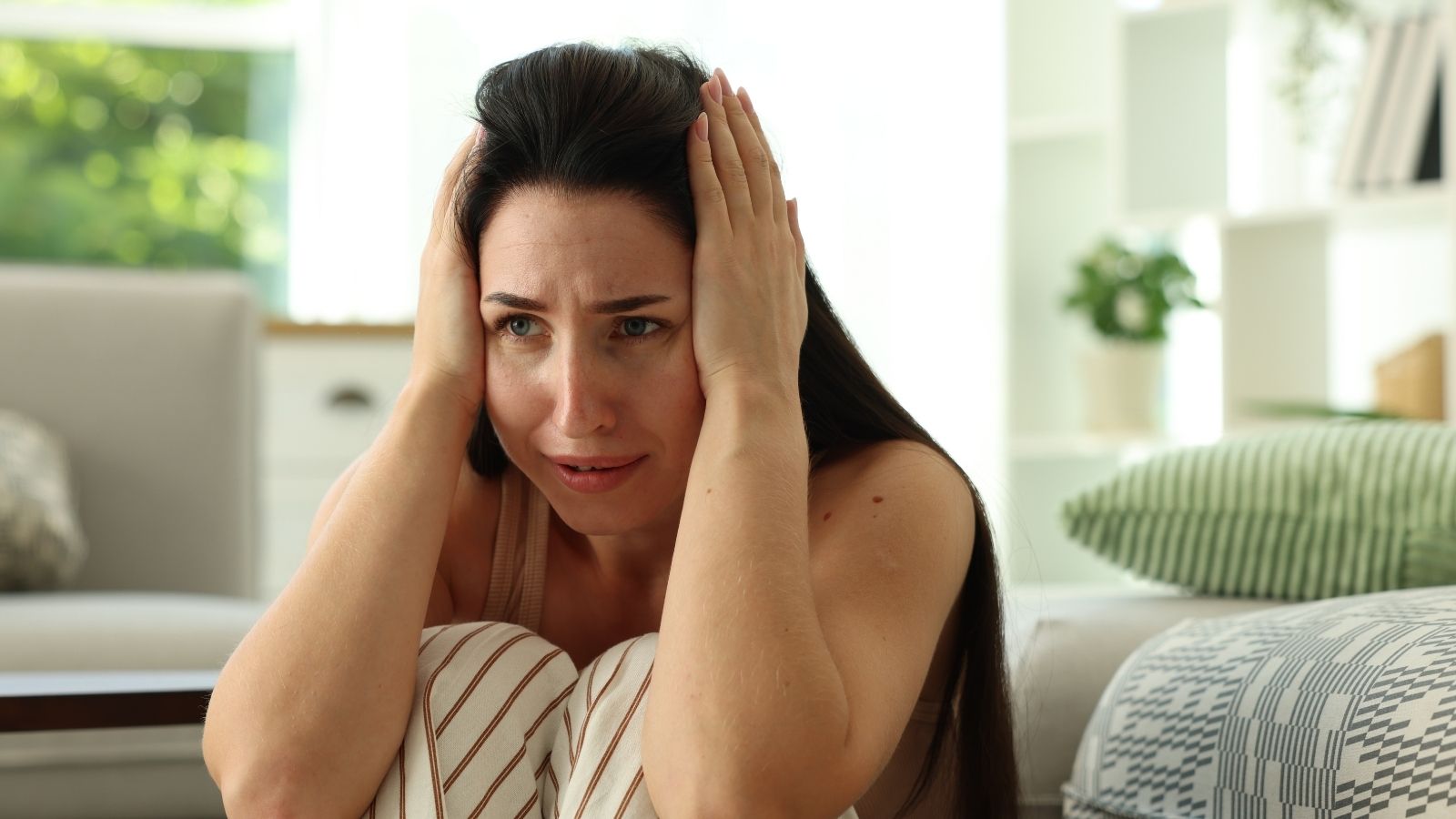 A Low Frequency Sound Won’t Stop Driving Her Crazy—So She’s Determined to Figure Out Where It’s Coming From stressed out woman sitting on the floor with her hands on her head