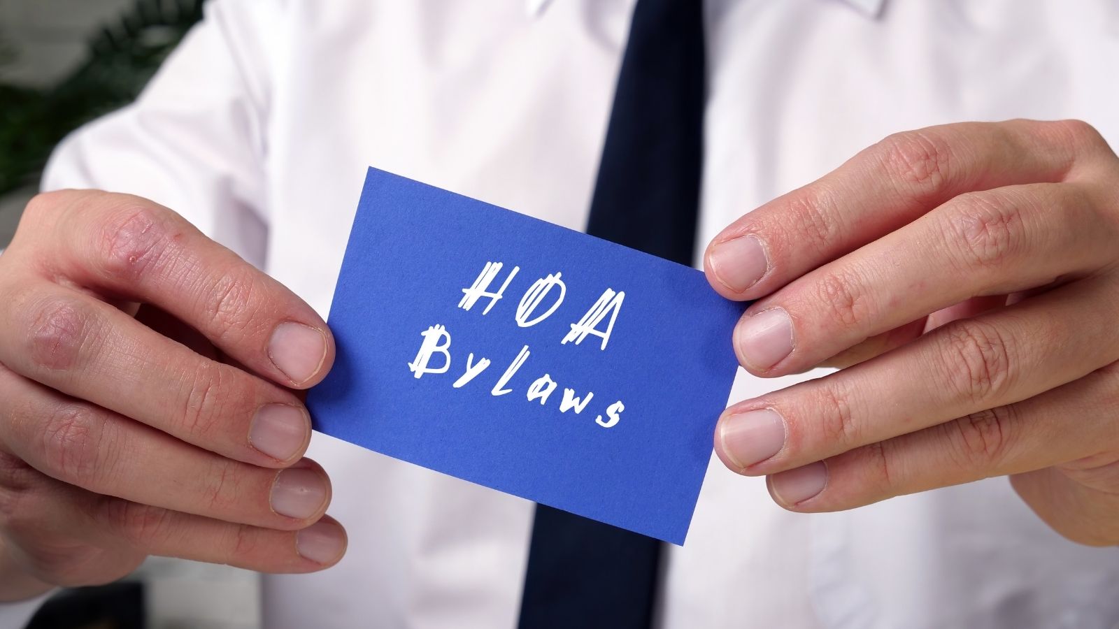 man holding a blue card that reads "HOA bylaws"