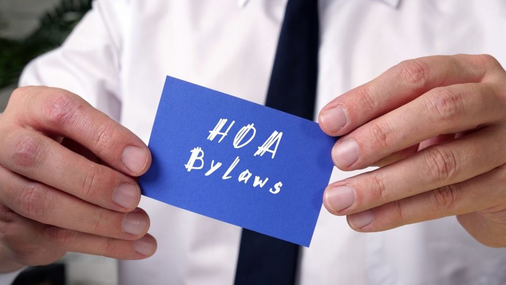man holding a blue card that reads "HOA bylaws"