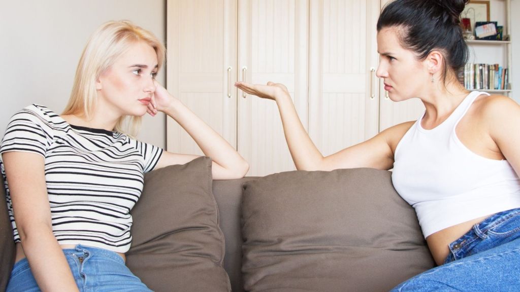 two female friends sitting on a couch arguing