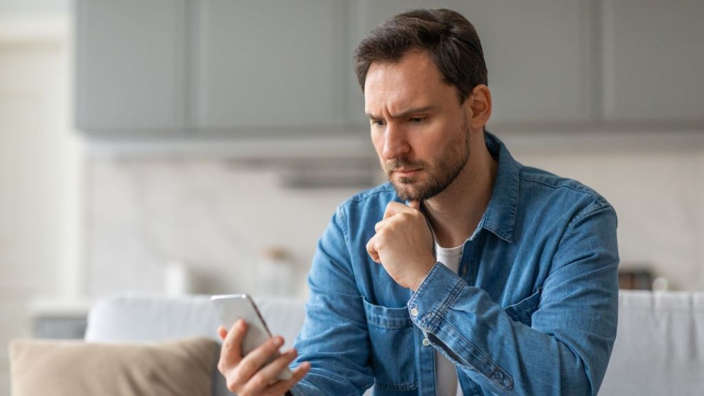 man looks concerned while looking at his phone