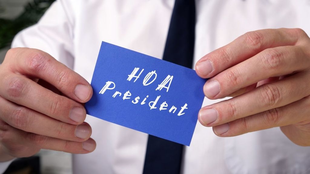 man holding a blue card that reads "HOA President"