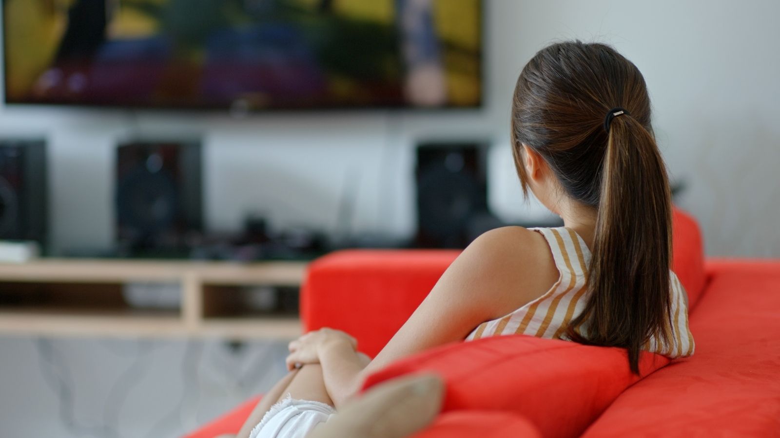 New to the Neighborhood, She Learned There Was an Unspoken Rule: Host a Welcome Party. She Wants No Part of It. woman sitting on the couch watching TV