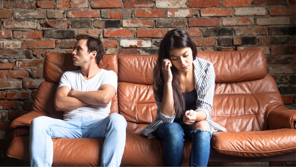 Upset looking couple sitting on a couch