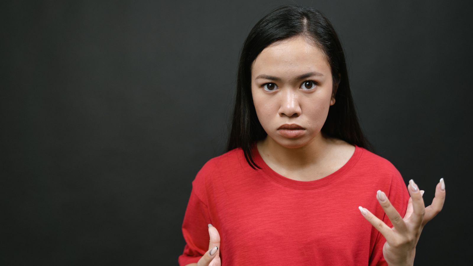 Woman Calls Out Sister After Affair With Another Sister’s Boyfriend, but Family Wants an Apology From the Whistleblower Angry woman in red shirt