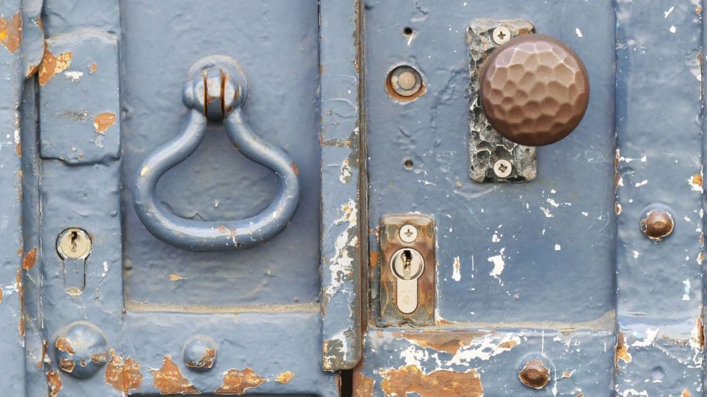 Old door knocker and door knob with peeling paint