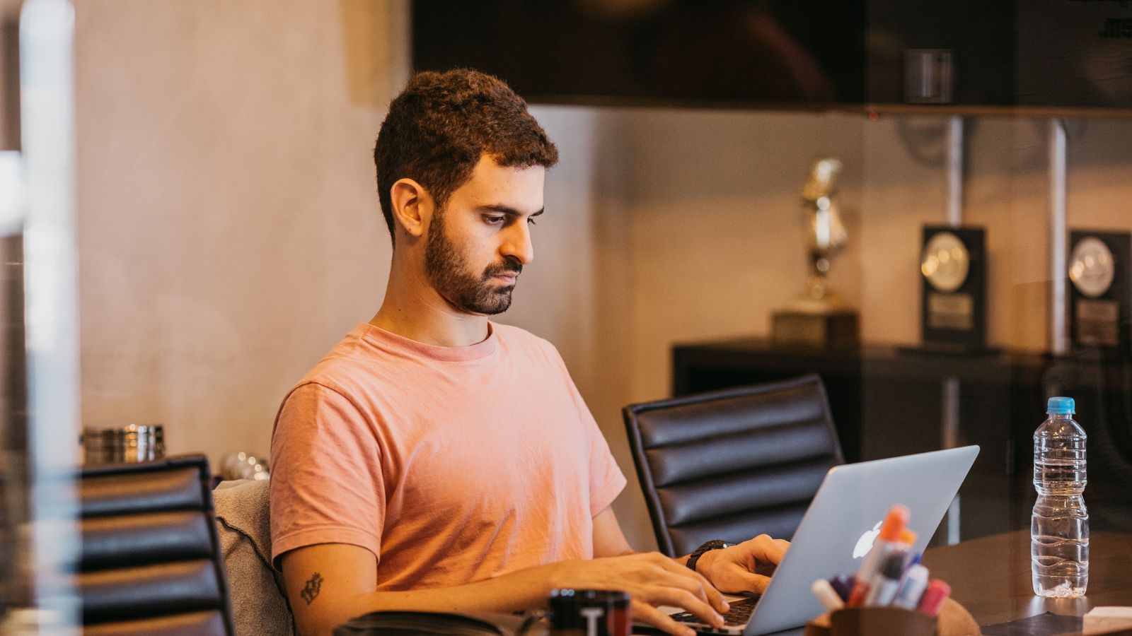 He Ignored My Warning and Spent Thousands: IT Employee Facing Fire Over Coworkers Illegal Charge Man in orange T-shirt working on a laptop