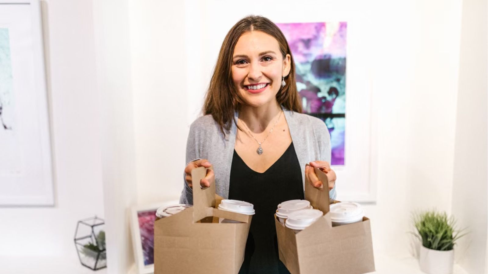 Woman holding to-go coffee cups for several people