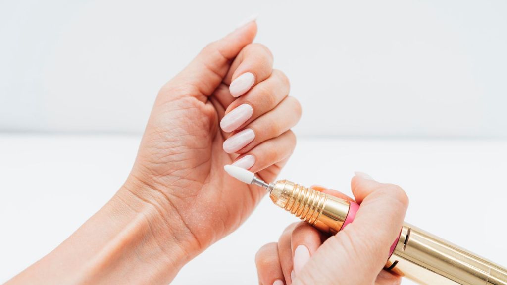 Woman using a nail file to maintain her long, white nails