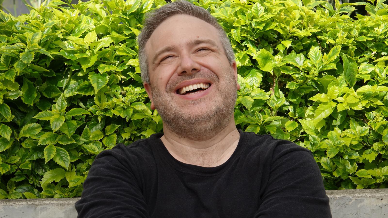 man laughing in front of some plants