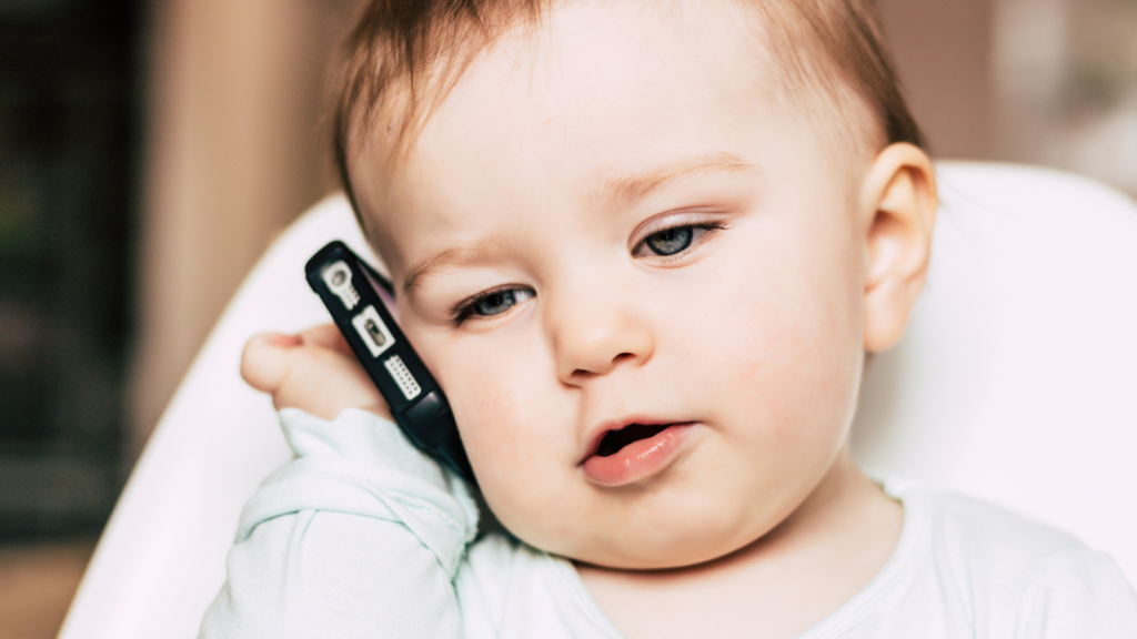 baby holding smartphone pretending to talk