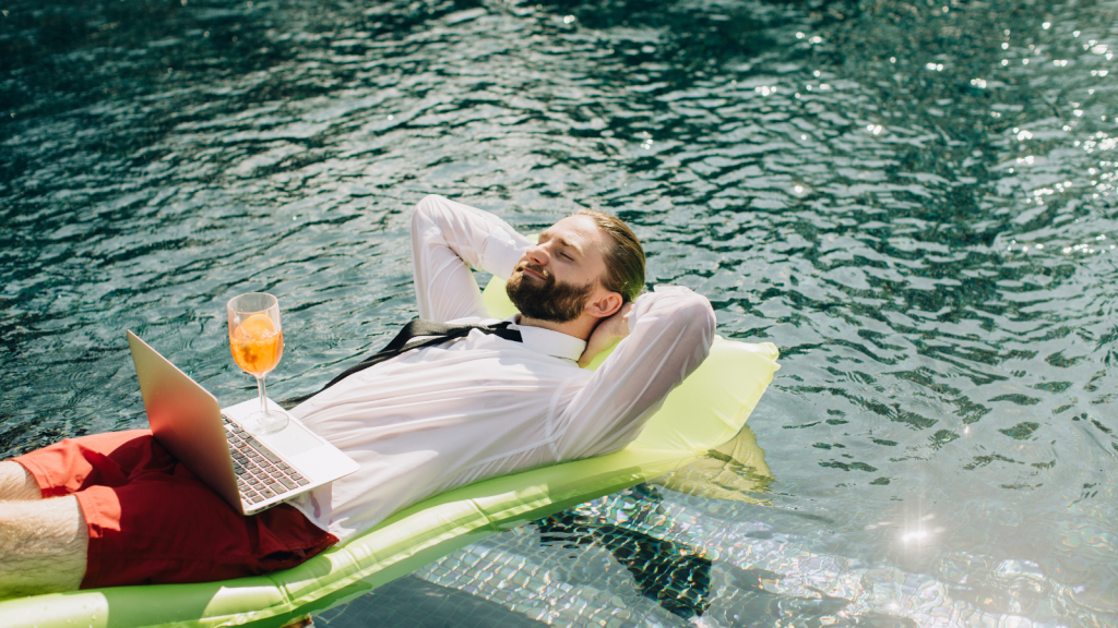 businessman laying back in pool with laptop