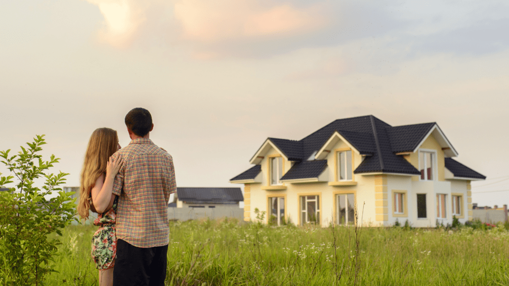 couple standing in field looking at very nice house