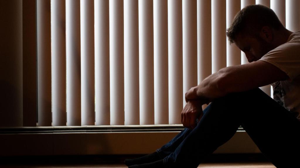 depressed man sitting by the window