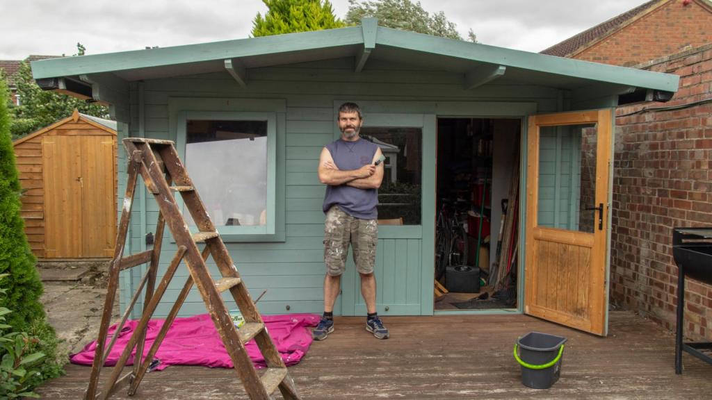 man standing in front of a shed
