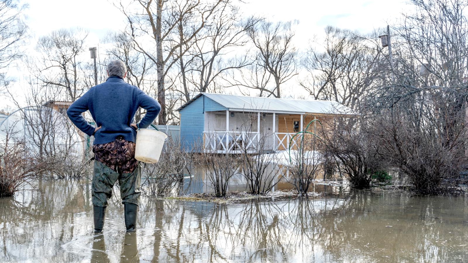 His Neighbors Refused to Fix a Drain Pipe in Their Yard—Now His Property Floods Every Time It Rains man standing in a flooded yard