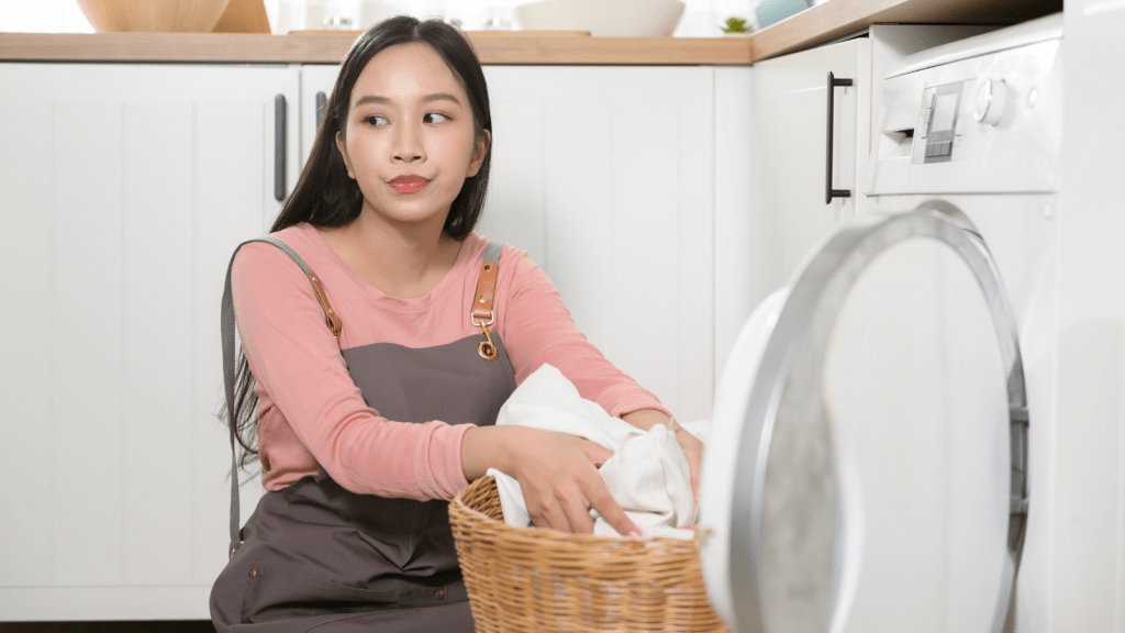 frustrated young woman sitting on the floor doing laundry