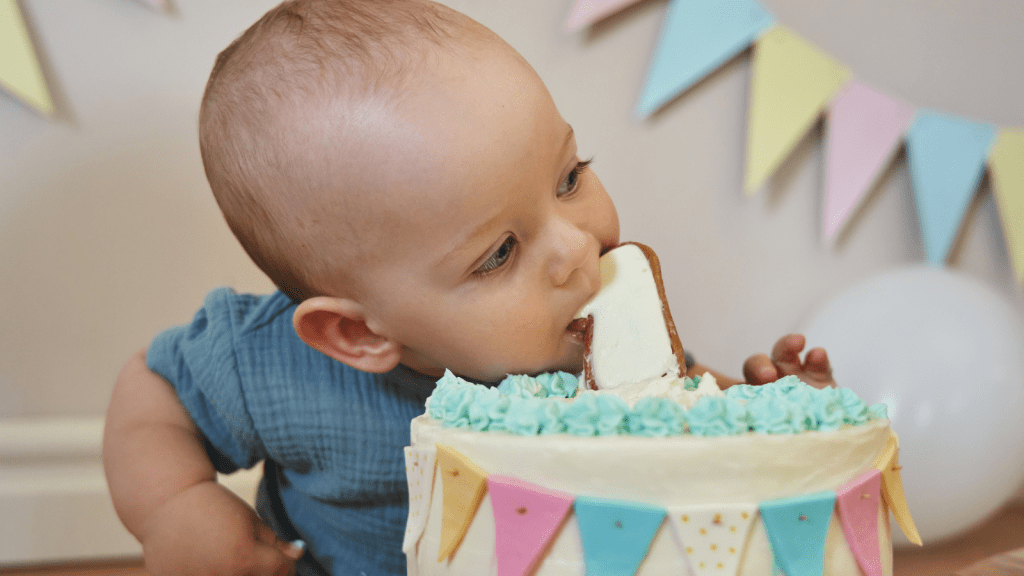 happy birthday 1 year old boy leaning in to eat cake