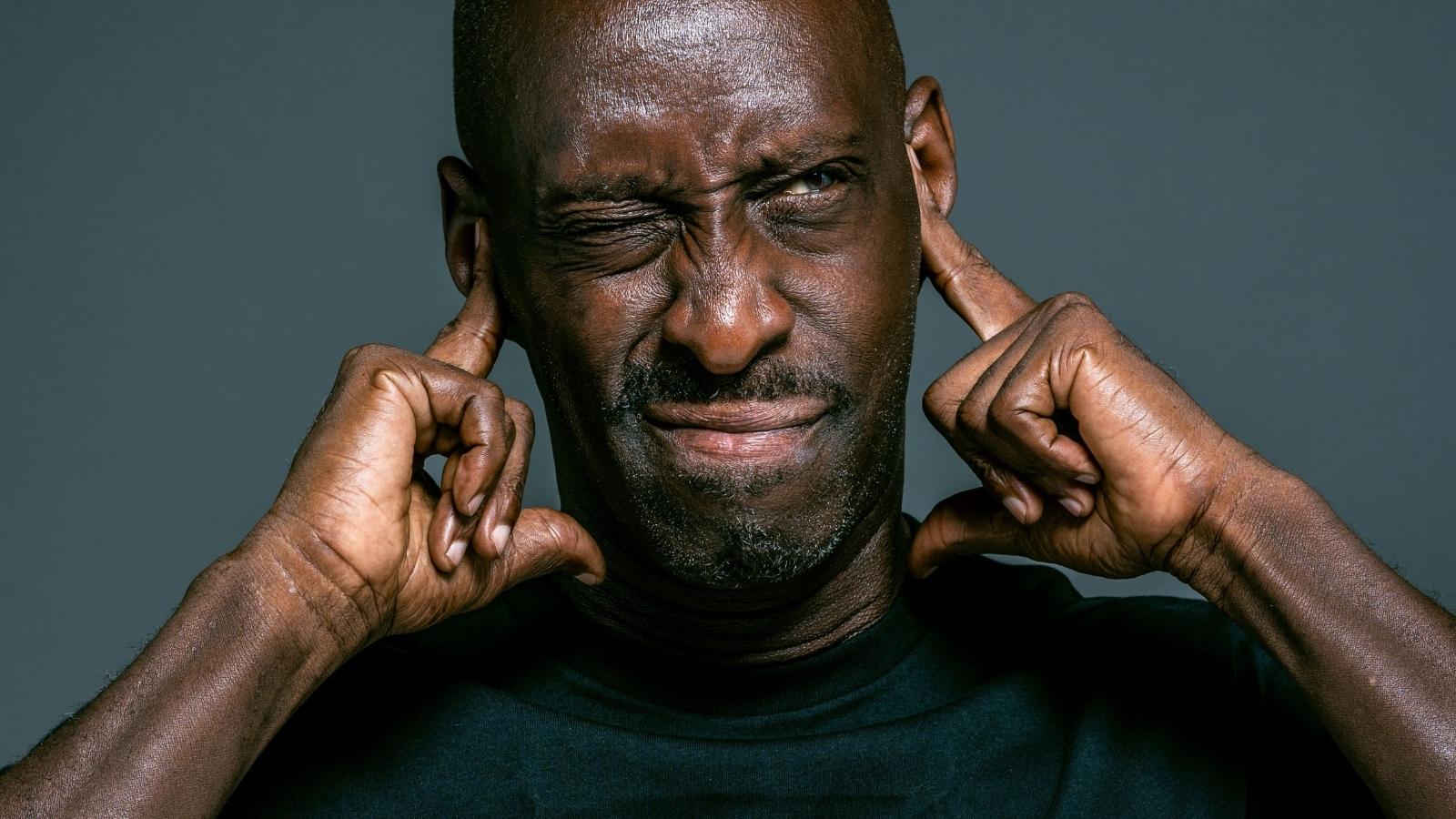 man covering his ears from loud noise