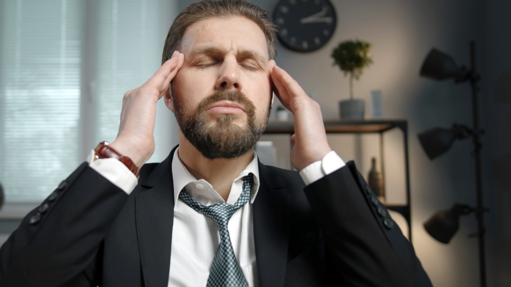 man rubbing temples at work