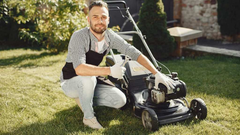 man sitting next to a lawn mower