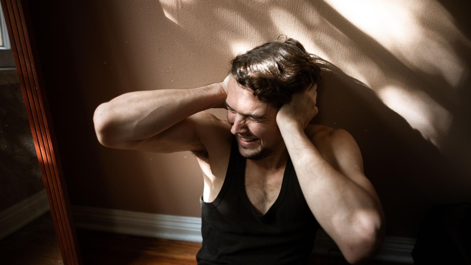 man sitting on the floor covering ears