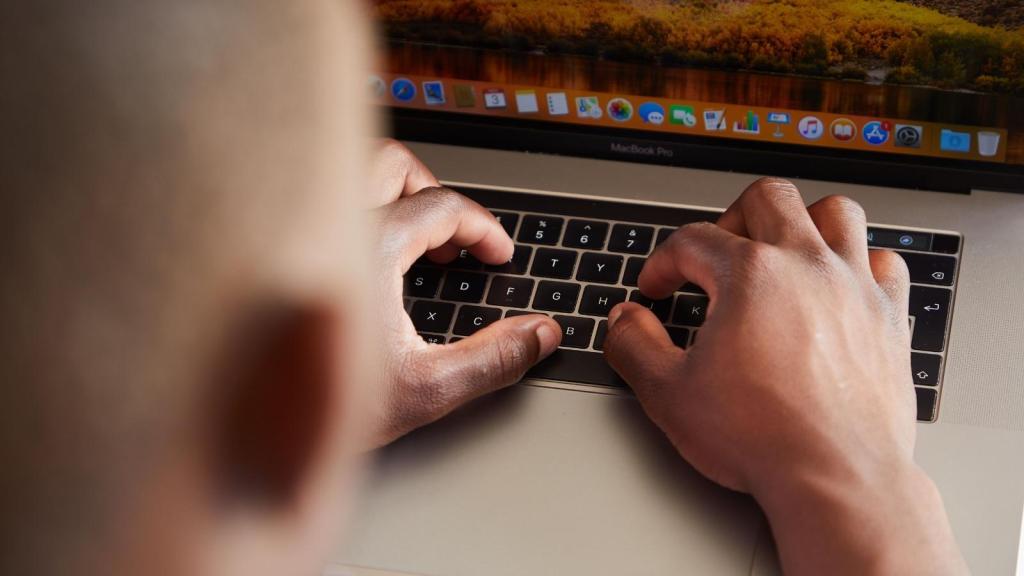 man typing on his macbook computer