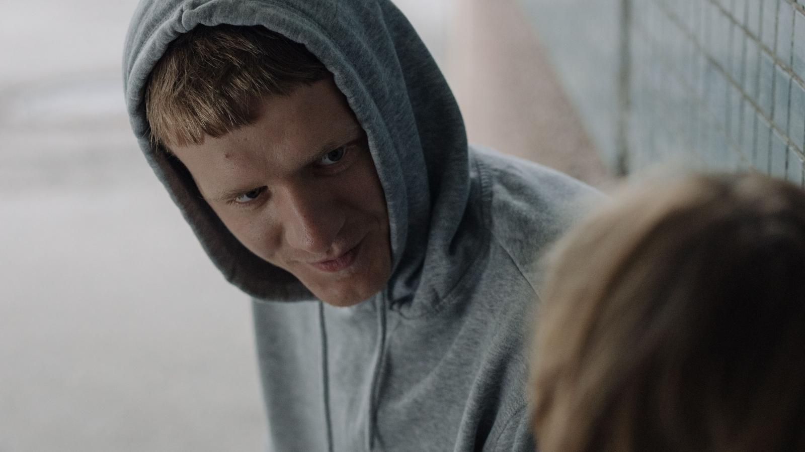 mischievous teen in gray hoodie