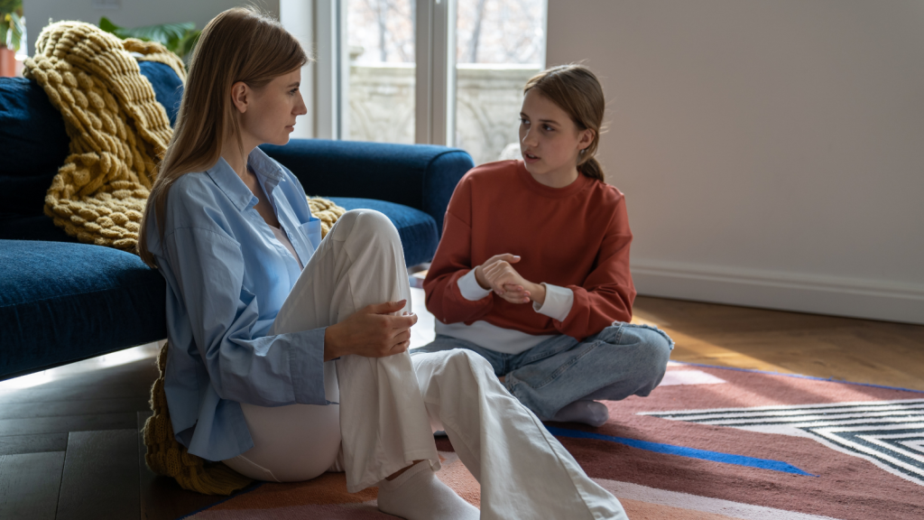 mother and teen daughter talking while sitting on floor