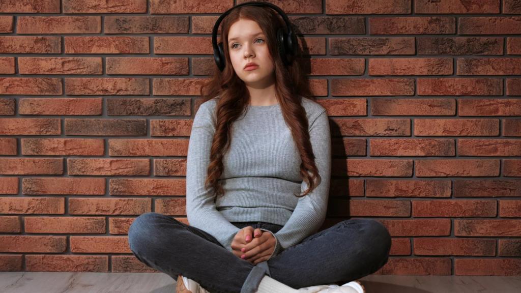 girl sitting against a brick wall