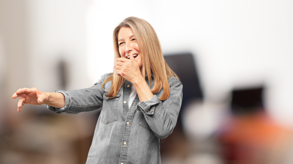 older woman laughing hysterically with hand over mouth