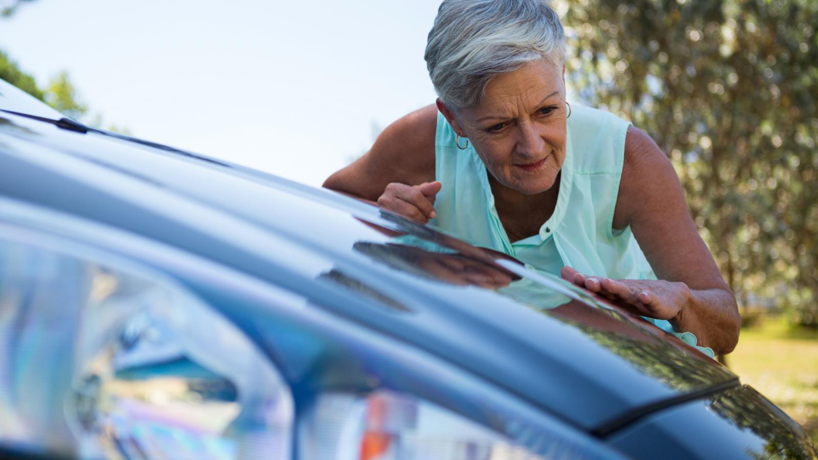 older woman looking at a car