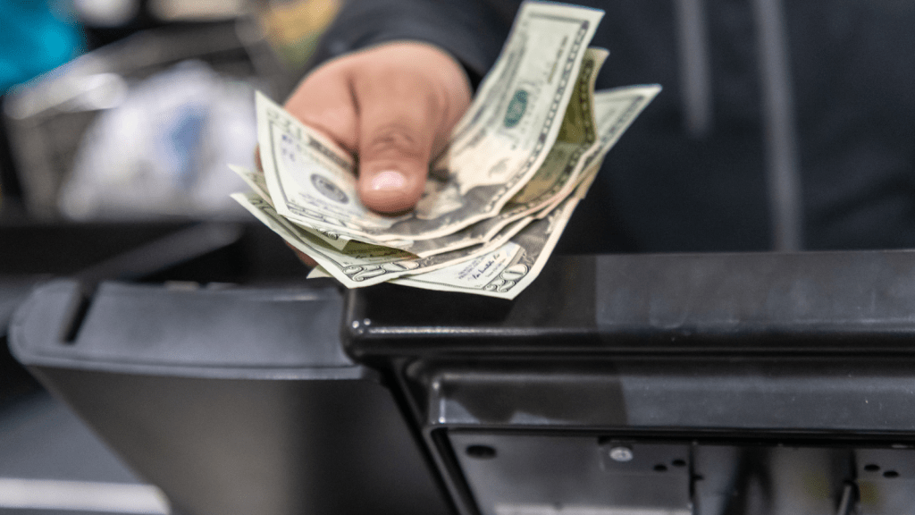person handing cash over the cash register