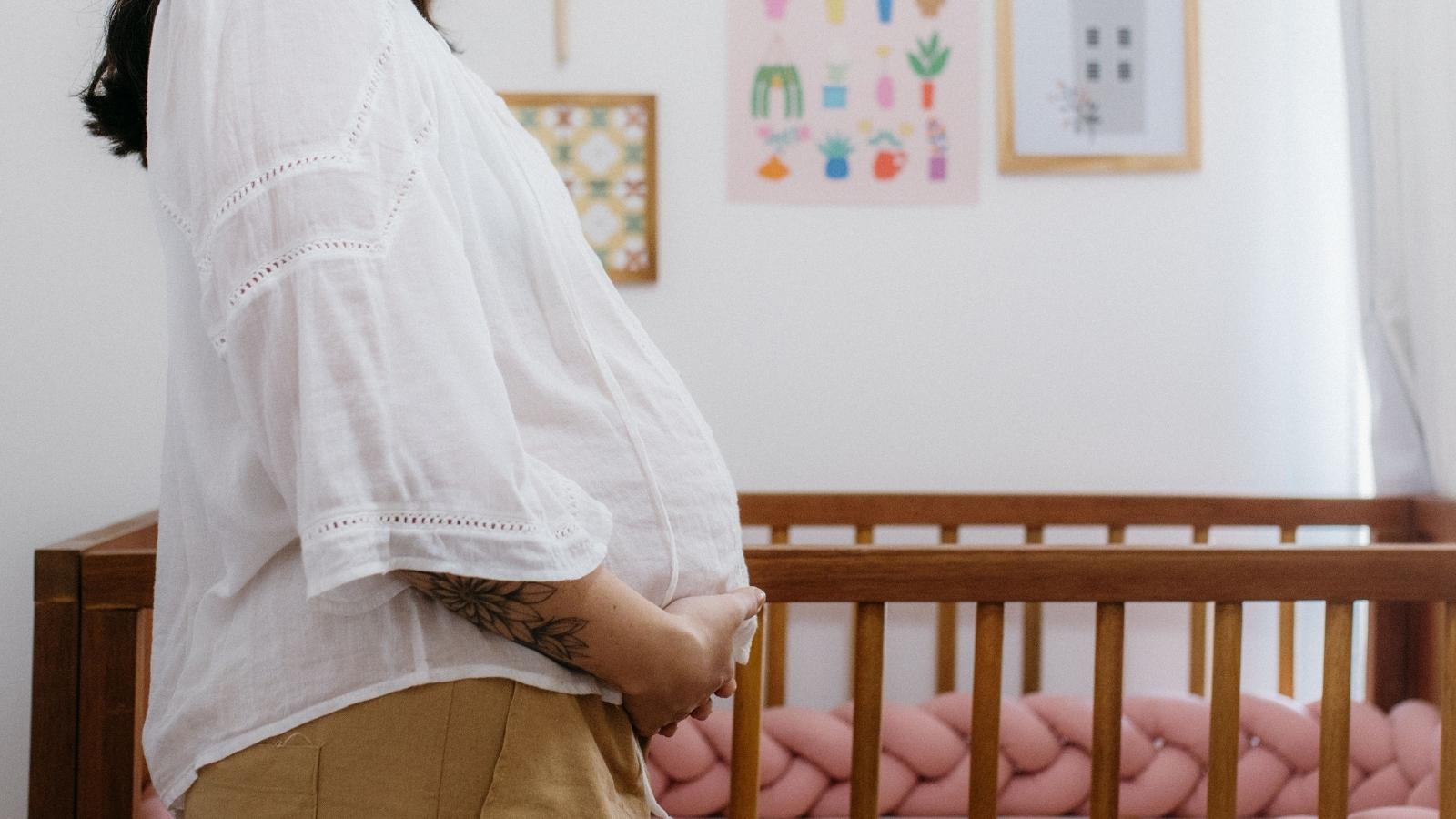 It Wasnt My Secret to Tell: Woman Outraged After Sister Brands Her a Traitor Over Pregnancy News pregnant woman standing by fridge