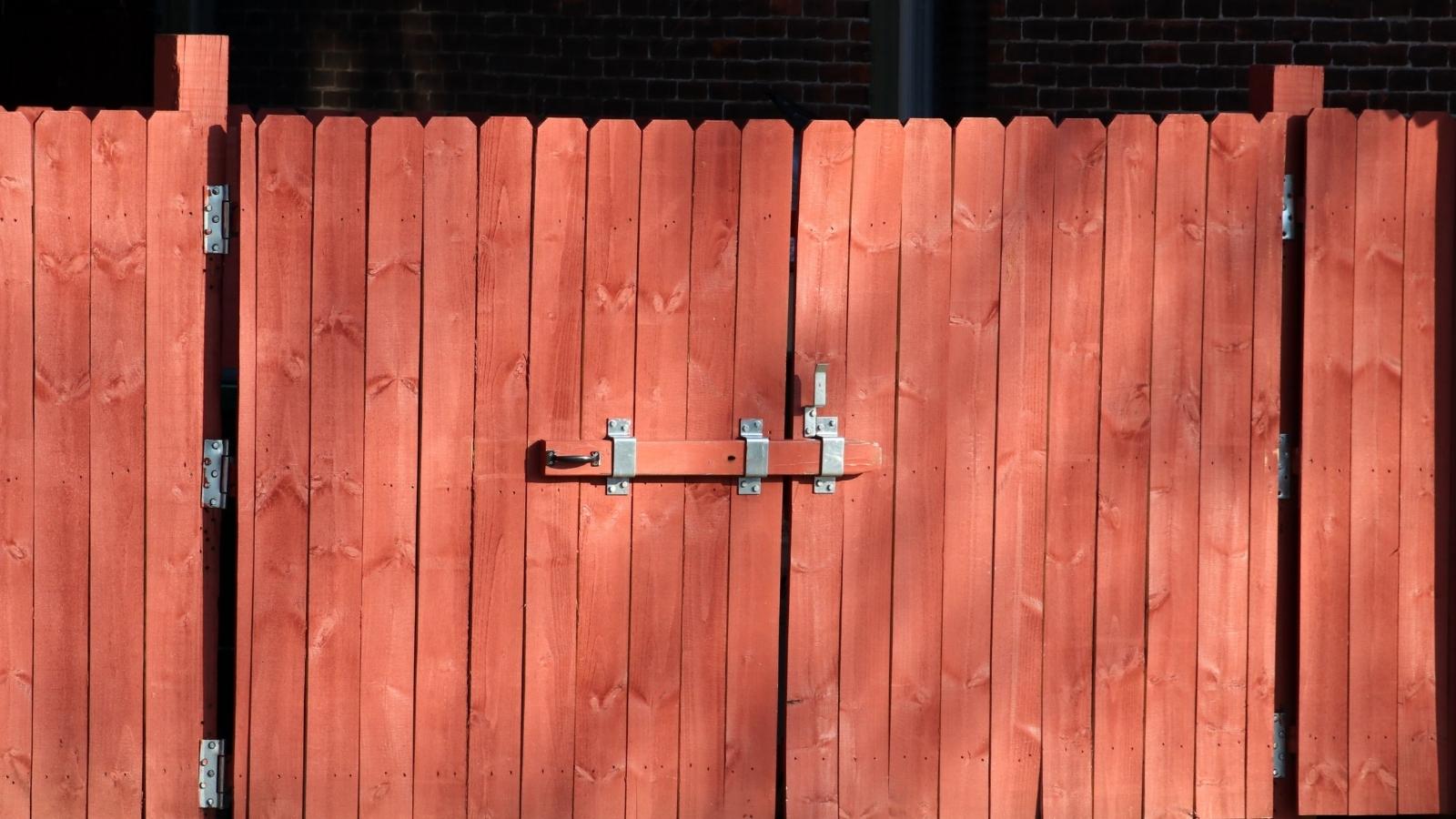 Safety Hazard: Woman Furious After Neighbor’s Party Night Exposes Her Property to Danger red wooden gate