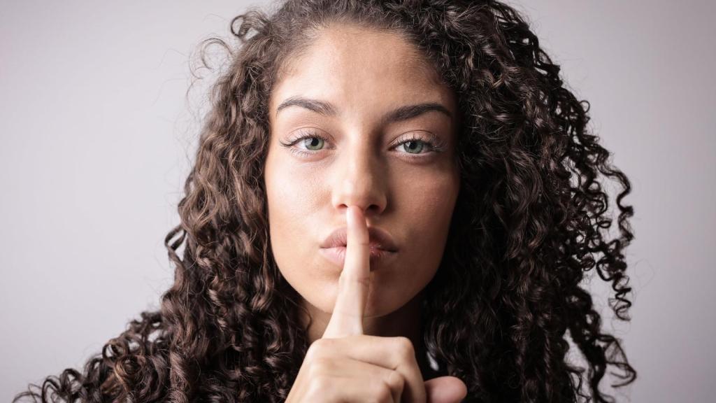 secretive woman with finger pressed on lips telling secret