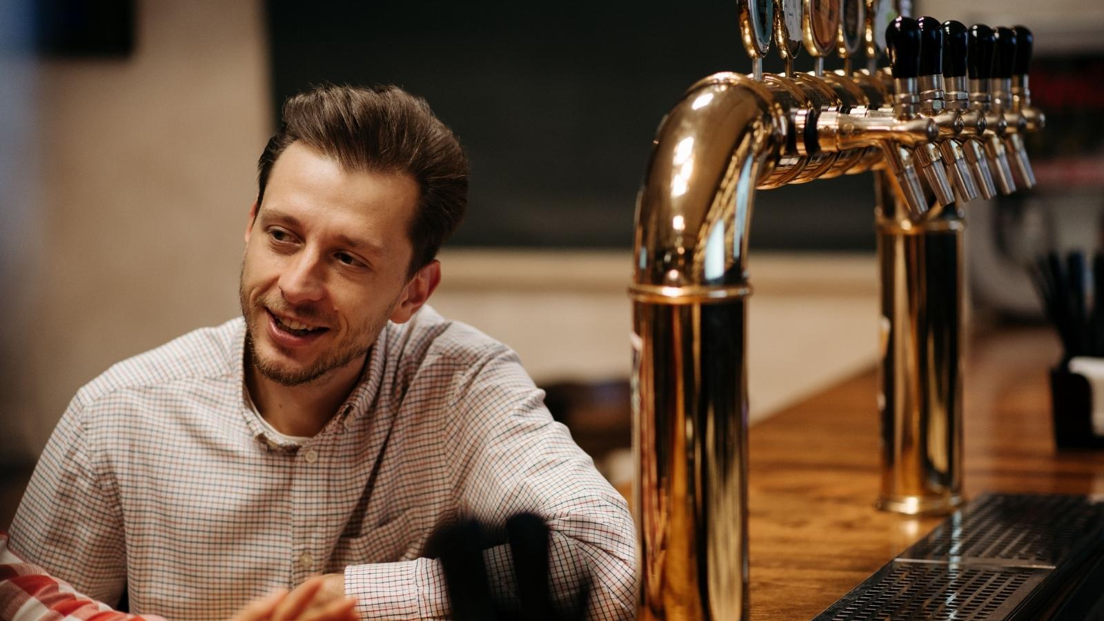 He Bought His Girlfriends Cousin a Birthday Drink as a Kind Gesture—But Her Aunt and Uncle Accused Him of Having Ulterior Motives smiling man sitting at the bar