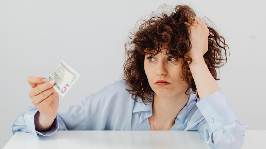 stressed woman looking at five dollar bill