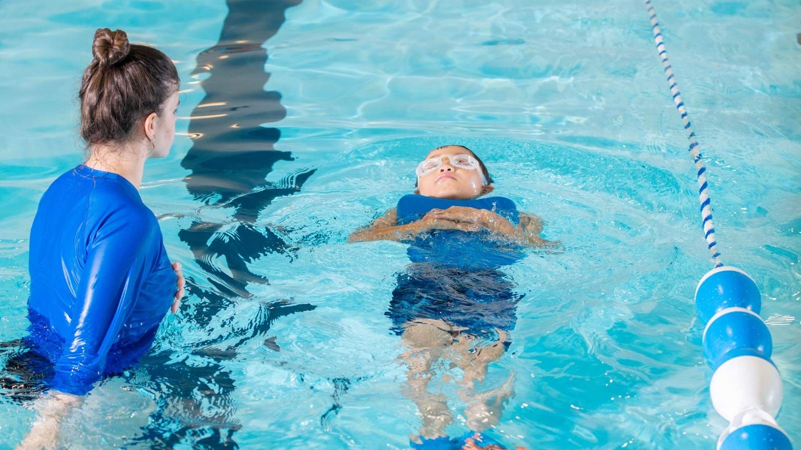 swim instructor teaching a kid to swim